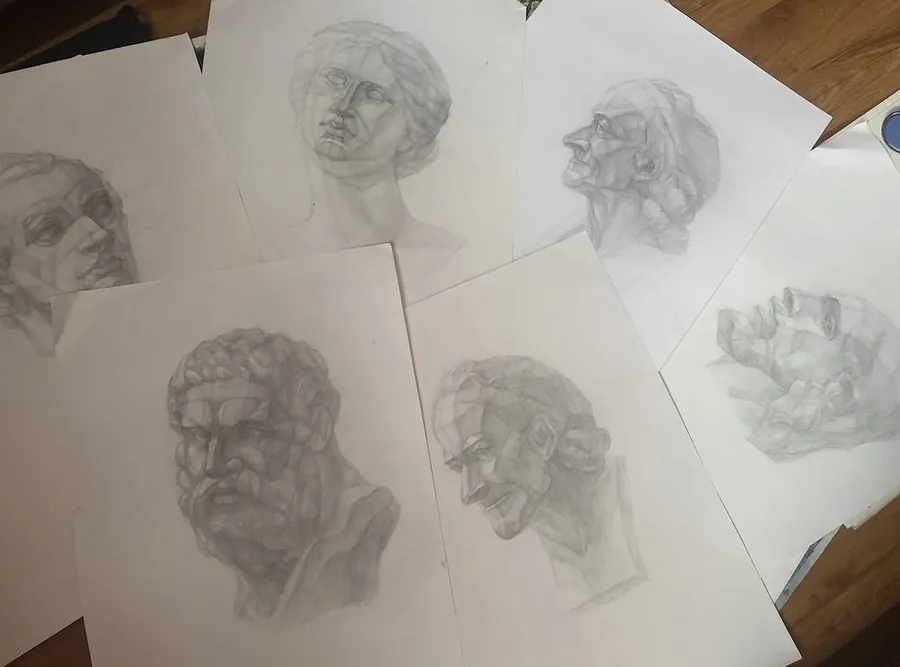 Pencil studies of classical plaster heads on loose sheets of paper.