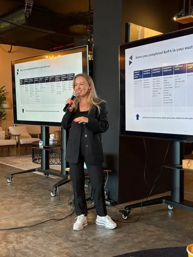 Kate V. speaking with a microphone between two screens showing a records-of-processing template.